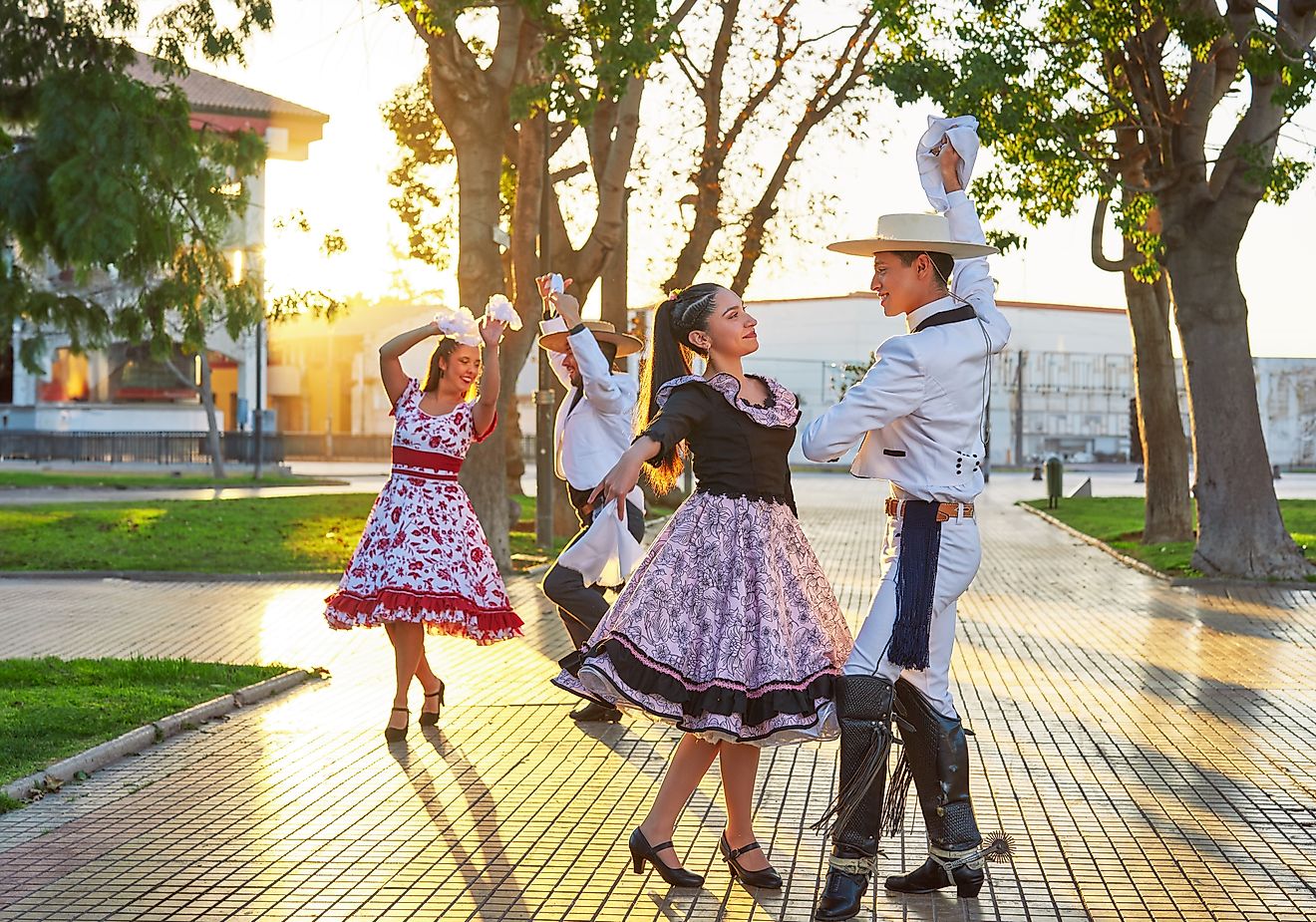At sunset in La Serena, Chile, two Latin American couples dressed as huasos dance cueca in the town square.